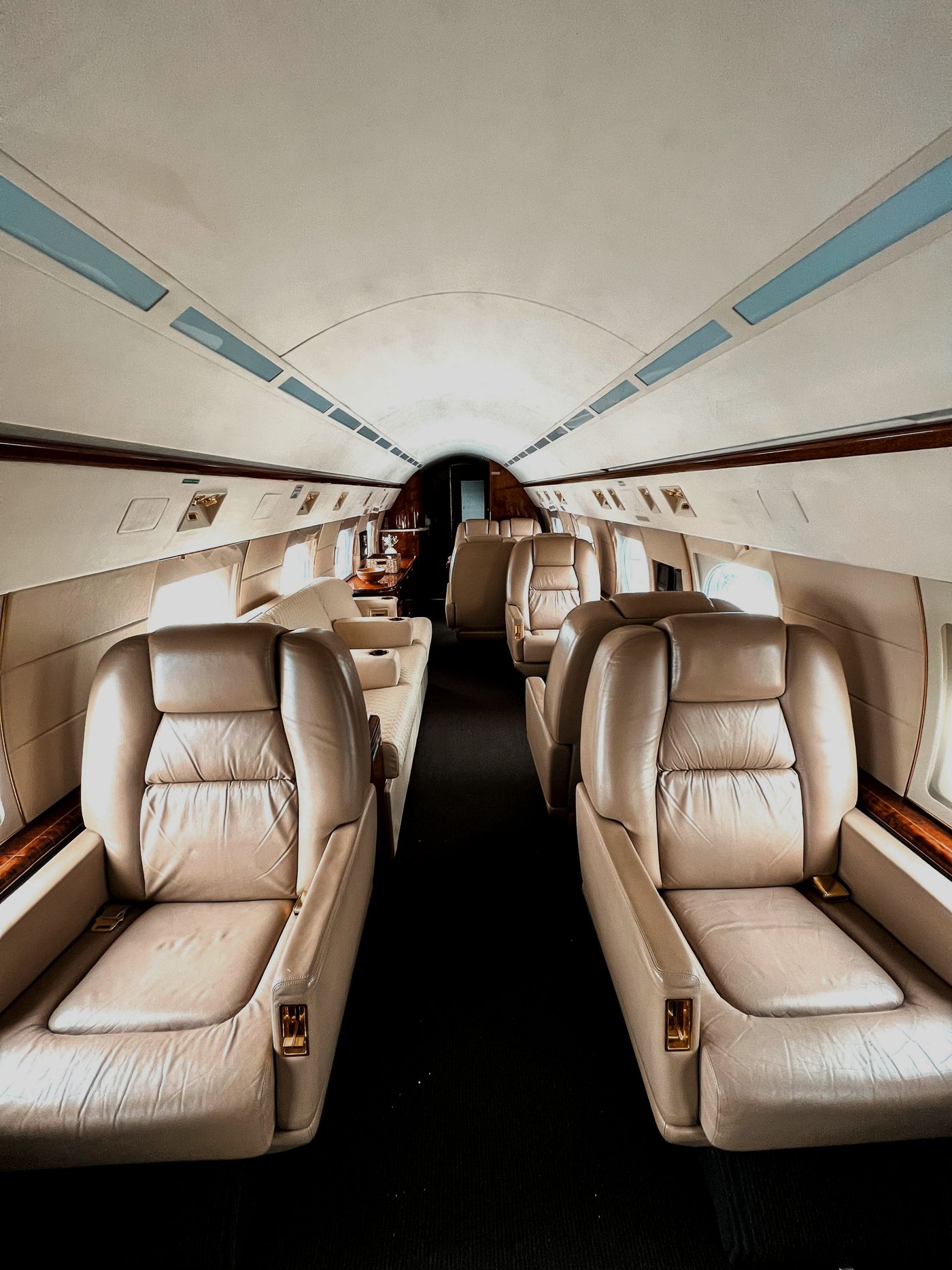 Business jet cabin aisle lined with cream leather club seats