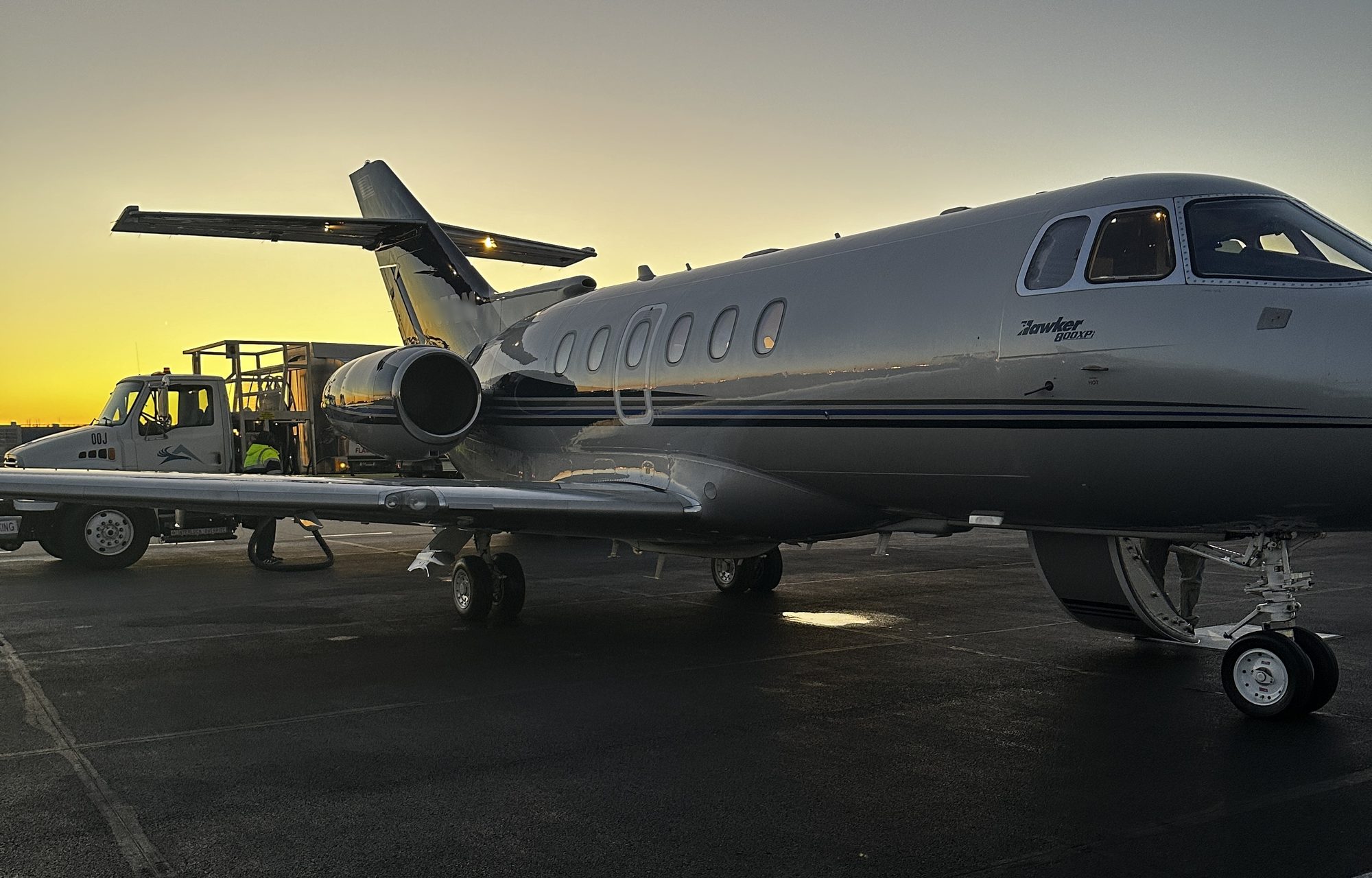 Hawker business jet on the ramp at sunrise with a fuel truck