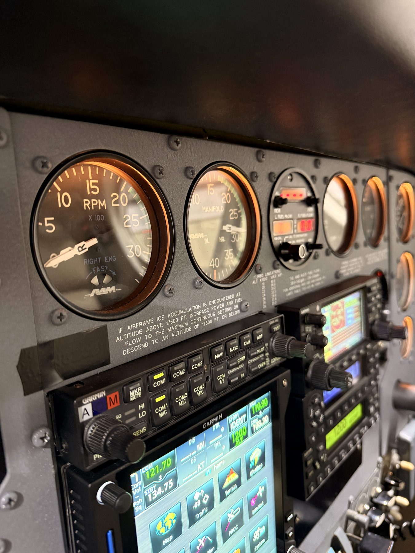Twin-engine panel gauges and Garmin avionics glowing in a dim cockpit