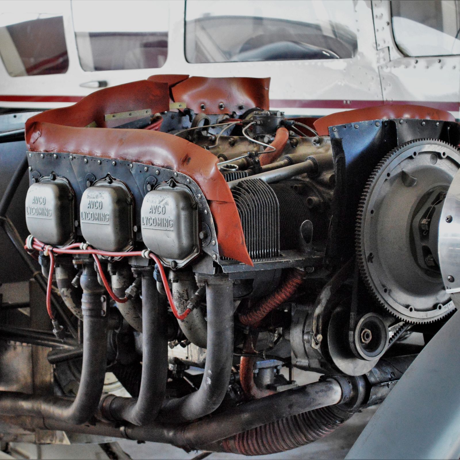 Piston aircraft with the cowling off, showing the cylinders and exhaust in the hangar